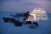 Tatigat, an inuk, pulls aside the snow brick over the igloo door at dusk. Igloolik. Nunavut. Canada. 1993