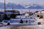 People walk in the streets of Pond Inlet on a warm June day. Bylot Is on the horizon Nunavut. Canadian Arctic. 1999