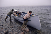 A small Cree boy holds his father's wooden canoe on a hunting trip. Northern Quebec, Canada. 1988
