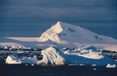 Light catching an iceberg echoes the shape of a snow covered mountain in Antarctica