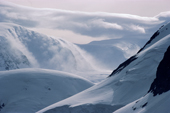 Clouds roll dowm the sides of glaciated mountains from the Polar Plateau. Antarctica
