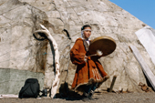 Chukchi girl in her dancing costume with a drum by a uranga (tent). Maynapylgino, Chukotka. Siberia, Russia.