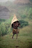 A Yali girl wearing a cape of Pandanus leaves to keep of the rain. Irian Jaya. Indonesia. 1990