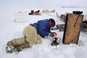 Inuit hunter, Qaaviganguaq lights a Primus stove to make tea during a rest on a Spring seal hunt. Moriussaq, Northwest Greenland. 1980