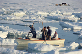 An Inuit family manouevre an an open boat through melting summer sea ice in Inglefield Bay. Thule, Northwest Greenland. 1980