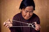 Mikivssuk, an Inuit woman from Qeqertat, makes a string puzzle, representing a fox. Avernersuaq, Northwest Greenland. (1980)