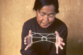 Inuit woman, Mikivssuk, makes a string puzzle depicting a porch between two houses. Thule, North Greenland. 1980