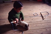 Inuit child, Peter, with whip and a husky pup. Qeqertat, NW Greenland. 1980