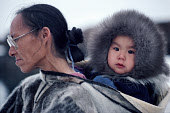 Inuit grandmother, Patdlunguaq carries Peter, in a seakskin Amaut (hooded jacket). Qeqertat, Northwest Greenland. (1980)