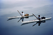Two Inuit hunters using kayaks in summer for seal hunting. Sealskin floats (Avataq) behind them. Northwest Greenland. (1980)