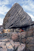 While at a summer Narwhal hunting camp, Ukujaq Duneq, an Inuit hunter, rests in a cavity under huge rock. Qeqertat, thule, Northwest Greenland. (1980)