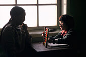 Aminguaq Imina, an Inuit woman, teaching her son,Agpalinguaq, Agpalinguaq, to use an abacus in their home at Siorapaluk. Robertson Fiord, Thule, Northwest Greenland. (1977)