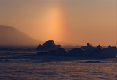 Caused by ice crystals in the atmosphere, a Parhelion above icebergs and sea ice in Northwest Greenland. 1998