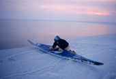 Qaerngak Nielsen, an Inuit hunter, checks his kayak at the ice edge near Cape York. N.W.Greenland. 1998