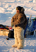 Simon Eliassen, an Inuit hunter from Savissavik,out seal hunting in the winter near Cape York. He is wearing traditional polar bear skin trousers & Kamik (boots), together with a caribou skin parka. Northwest Greenland. (1998)