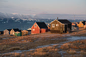 Houses in the Inuit community of Qaanaaq. Behind them is Inglefield Bay, with its water full of icebergs and bergy bits. Avanersuaq, Northwest Greenland.
