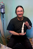 Putdlak Odak, an Inuit carver from Qaanaaq, holding a Tupilaq he has carved from a walrus tusk. Qaanaaq, Northwest Greenland (2022)