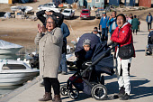 Inuit spectators gather at the harbour to watch an annual summer kayak race at Qaanaaq. Northwest Greenland. (2022)