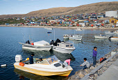 Inuit children playing amongst the hunters' boats in the harbour at Qaanaaq during the summer. Northwest Greenland. (2022)