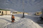 A woman walking among the modern houses in the Yupik Eskimo village of New Chaplino. Chukotskiy Peninsula, Siberia, Russia. 2010