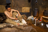 Inside the Polog (inner tent) of his Yaranga, Chukchi reindeer herder, Grisha Rahtyn, dresses entirely in traditional reindeer skin clothing. Chukotskiy Peninsula, Chukotka, Siberia, Russia. 2010