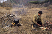 A Chukchi reindeer herder prepares a meal of reindeer meat while out at his herd's autumn pastures near Khailino. Koryakia, Kamchatka, Siberia, Russia. 1999
