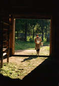 Valla, carrying a bucket of moose milk into a barn at the Sumarokova moose farm. Kostroma, Russia. 2002