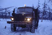 An Ural truck carrying supplies on a winter road in taiga at dusk. Northern Evensk, Magadan Region, E. Siberia, Russia. 2006