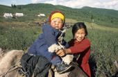 A young Tuvan woman holds a child sitting on a reindeer. Todzhu, Tuva, Siberia, Russia. 1998