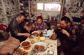 A Dolgan family of reindeer herders having a meal together inside their balok (a moveable hut built on sled runners). Taymyr, Northern Siberia, Russia. 2004
