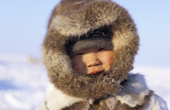Dolgan boy at a reindeer herders' camp, dressed in traditional furs. Taymyr, Northern Siberia, Russia. 2004