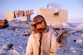 A young Dolgan boy stands outside his family's balok (wooden hut built on sled runners)on the tundra. Taymyr, Northern Siberia, Russia. 2004