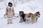 Nadiya Asyandu, a Nganasan woman, dressed in traditional clothing, standing by a dog team. Taymyr, Northern Siberia, Russia. 2004