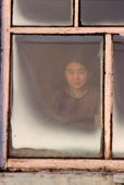 Lena Potapova looks through a frosted window at her home in Verkhoyansk, Yakutia, Siberia, Russia. 1999