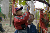 At an indigenous peoples festival, a young Forest Nenets girl attaches a ribbon to a sacred tree and makes a wish. Tarko-Sale, Purovsky, Yamal, Western Siberia, Russia