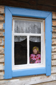 Maria Longortova, an elderly Khanty woman, at the window of her log cabin on the bank of the Synya River. Yamal, Western Siberia, Russia
