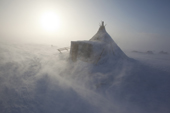 During a Spring storm, blowing snow swirls around a Nenets reindeer herders' camp on the tundra near Tambey. Yamal Peninsula, Western Siberia, Russia