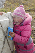 Angelina Laptander, a Nenets girl, holds a bar of chocolate she will eat during a day's travel by reindeer sled on the autumn migration. Yamal Peninsula, NW Siberia, Russia