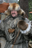 Market stall holder in a wolf skin coat with a bear paw on his chest, traditional craft market, Jokkmokk. Sweden. Size to A4