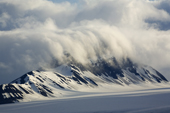 Clouds roll over a small mountain range in a glacier Spitsbergen